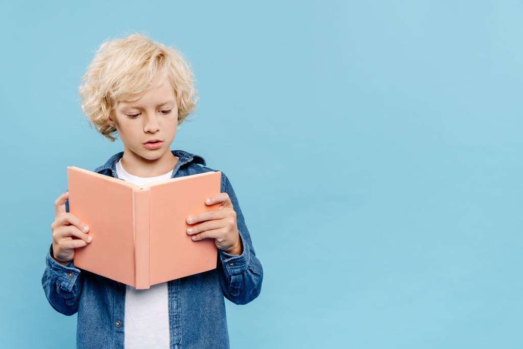 blonde and cute kid reading book isolated on blue  - Photo, Image