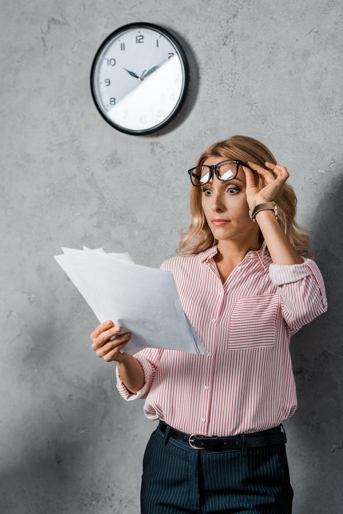 atraktivní a šokovaná podnikatelka s brýlemi při pohledu na papíry  - Fotografie, Obrázek