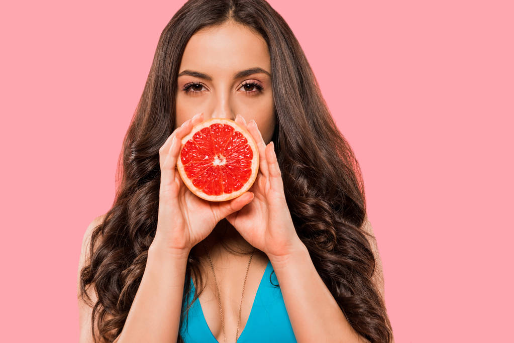 fiatal nő fürdőruhában borító arc fél grapefruit izolált rózsaszín  - Fotó, kép