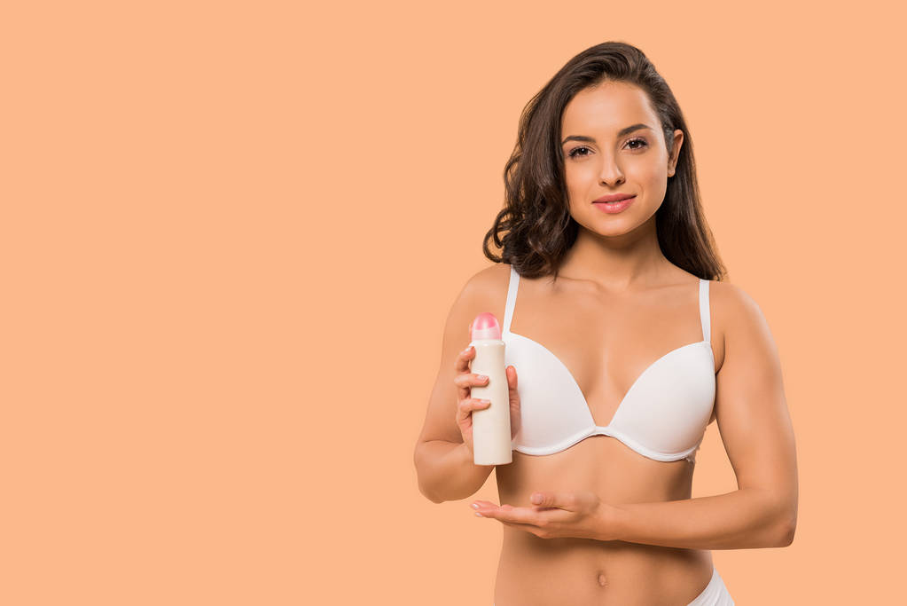 aantrekkelijke vrouw houden deodorant spray geïsoleerd op beige  - Foto, afbeelding