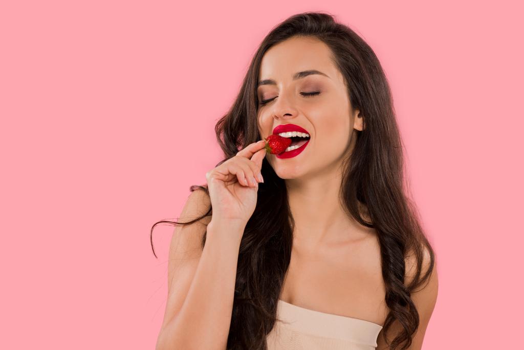 happy woman with red lips eating strawberry isolated on pink  - 写真・画像