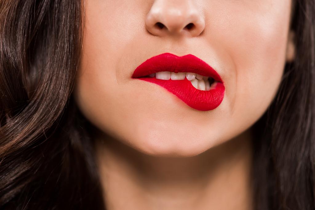 обрезанный вид молодой женщины, кусающей красные губы
  - Фото, изображение