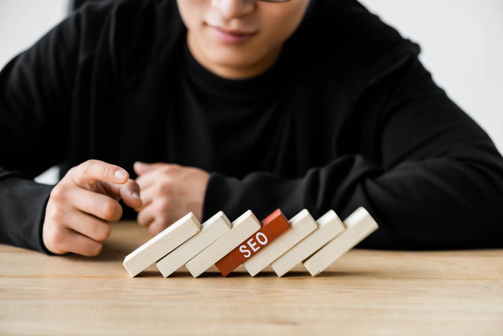 cropped view of seo manager pointing with finger at wooden rectangles with lettering seo  - Photo, Image