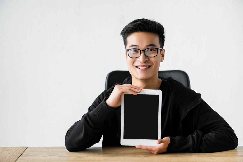 smiling asian hacker holding digital tablet with copy space - Photo, Image