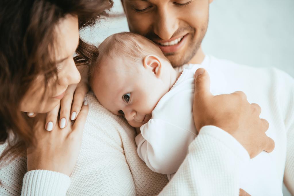 corte vista de feliz homem segurando adorável bebê perto sorrindo esposa
 - Foto, Imagem