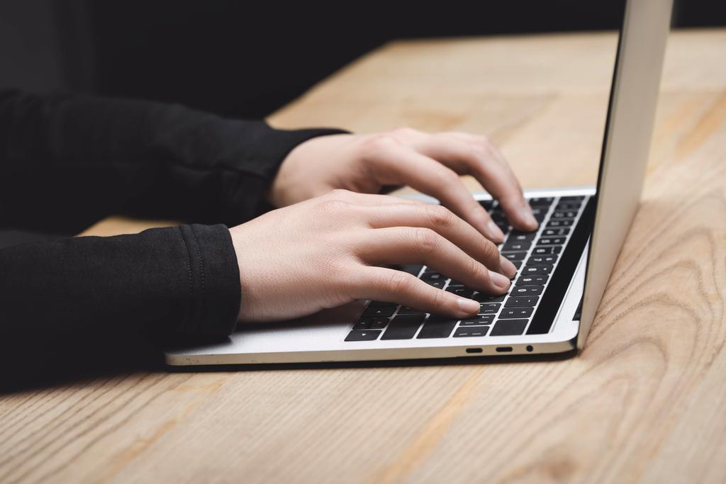 обрезанный вид хакера с помощью ноутбука и сидя за столом
  - Фото, изображение