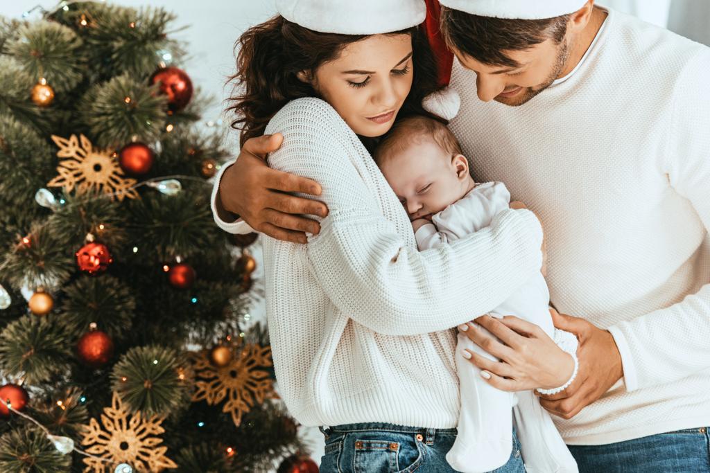 幸せな父親抱擁妻保持かわいい赤ちゃんクリスマスツリーの近く - 写真・画像