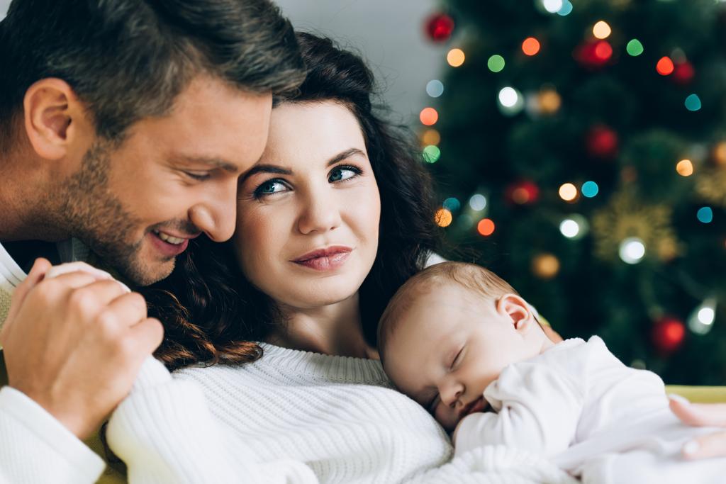 happy man touching hand of smiling wife holding sleeping baby - Photo, Image