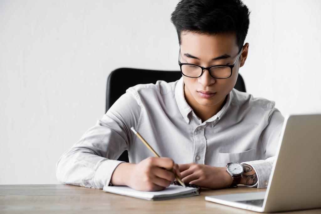 asiático seo manager escritura en notebook durante webinar en oficina
  - Foto, Imagen