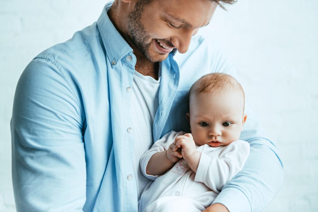 szczęśliwy ojciec uśmiecha się trzymając uroczą córeczkę - Zdjęcie, obraz