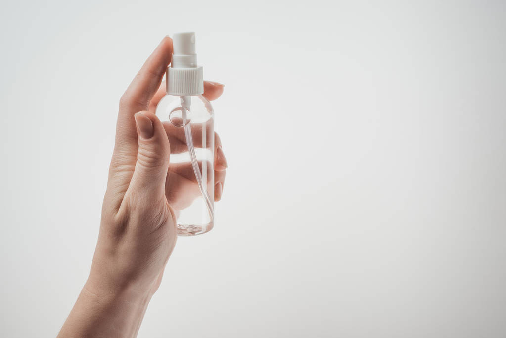обрезанный вид женщины, держащей бутылку с жидкостью на белом фоне
  - Фото, изображение