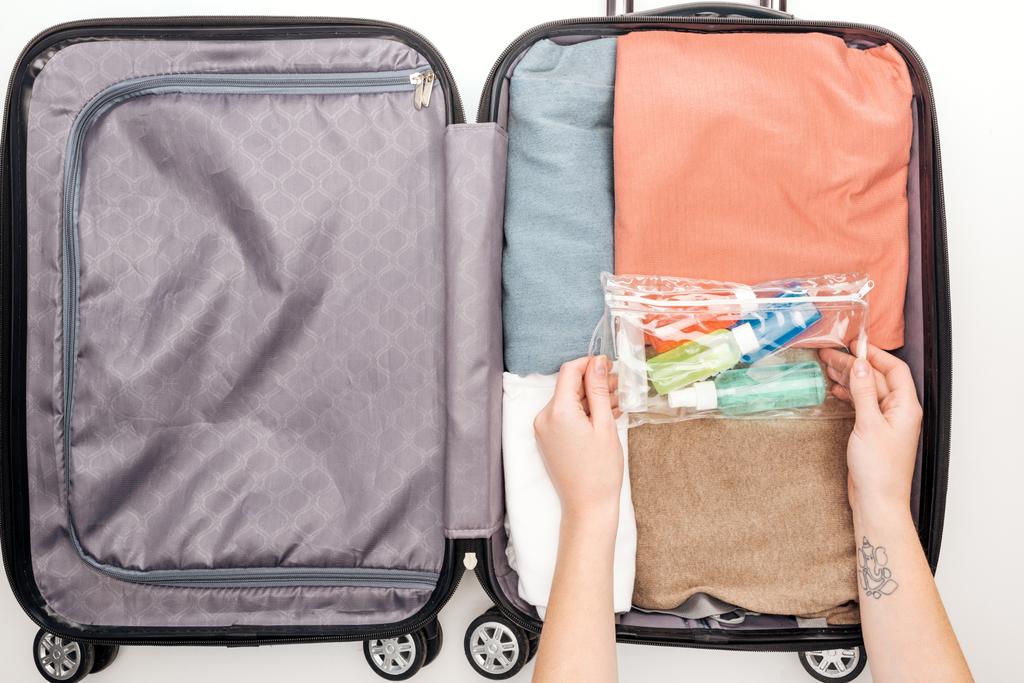 Ausgeschnittene Ansicht der Frau beim Einpacken der Reisetasche auf weißem Hintergrund  - Foto, Bild