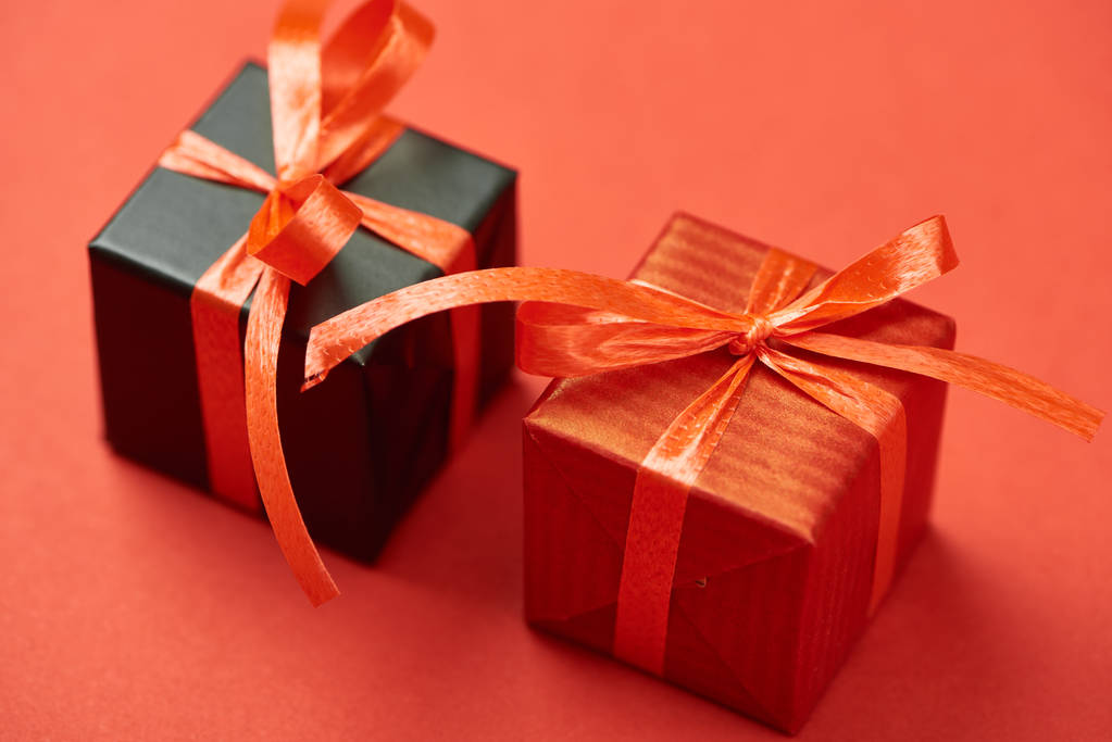 cajas de regalo con cintas y lazos sobre fondo rojo
 - Foto, Imagen
