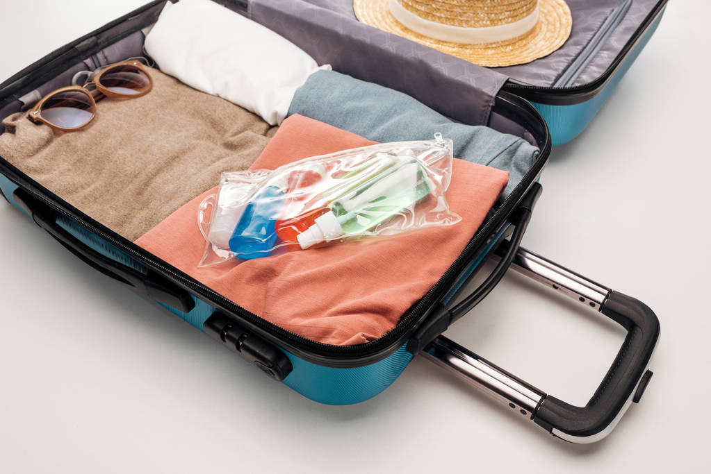 saco de viagem com toalha, saco cosmético com garrafas, roupas, óculos de sol e chapéu
  - Foto, Imagem