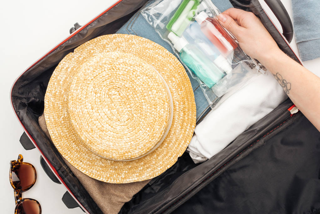 cropped view of woman packing travel bag with cosmetic bag with colorful bottles - Photo, Image