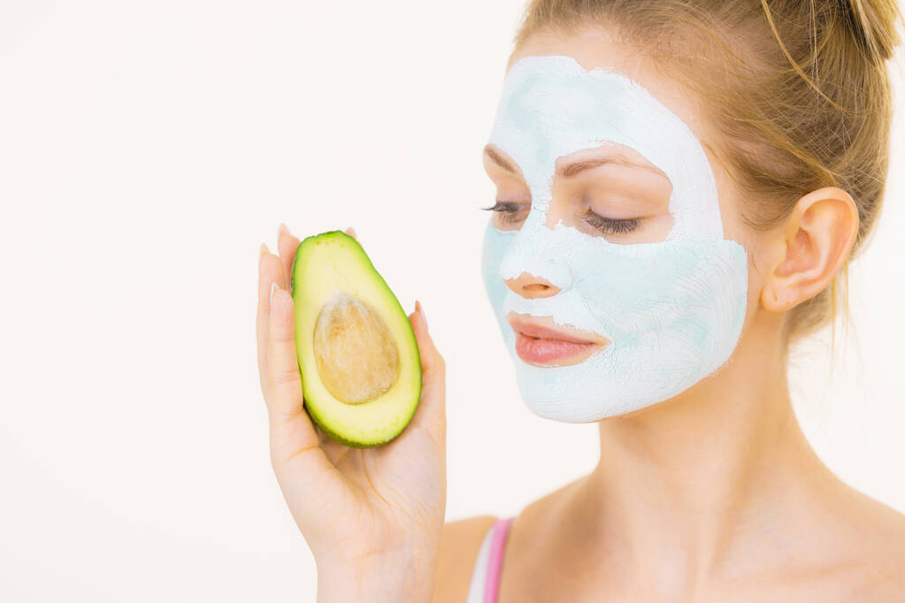 Menina máscara de lama facial detém frutas de abacate
 - Foto, Imagem