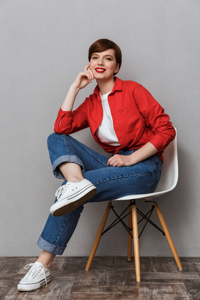 Изображение привлекательной молодой женщины, улыбающейся сидя на стуле
 - Фото, изображение
