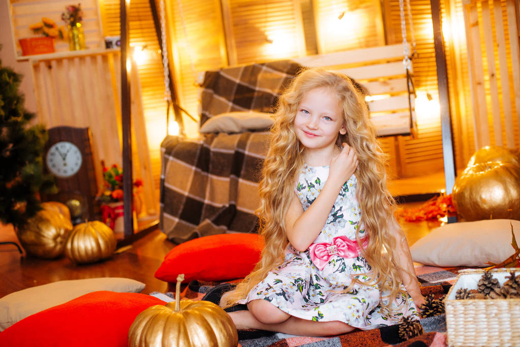 Menina bonito da idade escolar com cabelos longos loiros em um estúdio de outono com folhas amarelas, xadrez, abóboras e maçãs
 - Foto, Imagem