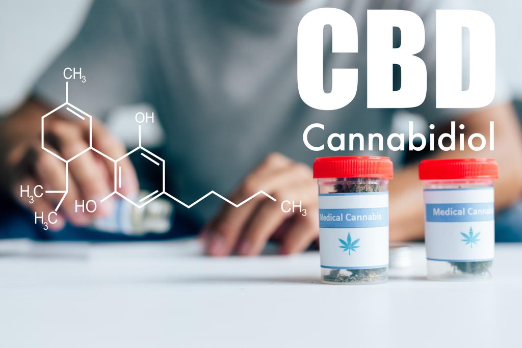 enfoque selectivo de botellas con cannabis medicinal en la mesa con el hombre en el fondo con ilustración de moléculas de cbd
 - Foto, Imagen
