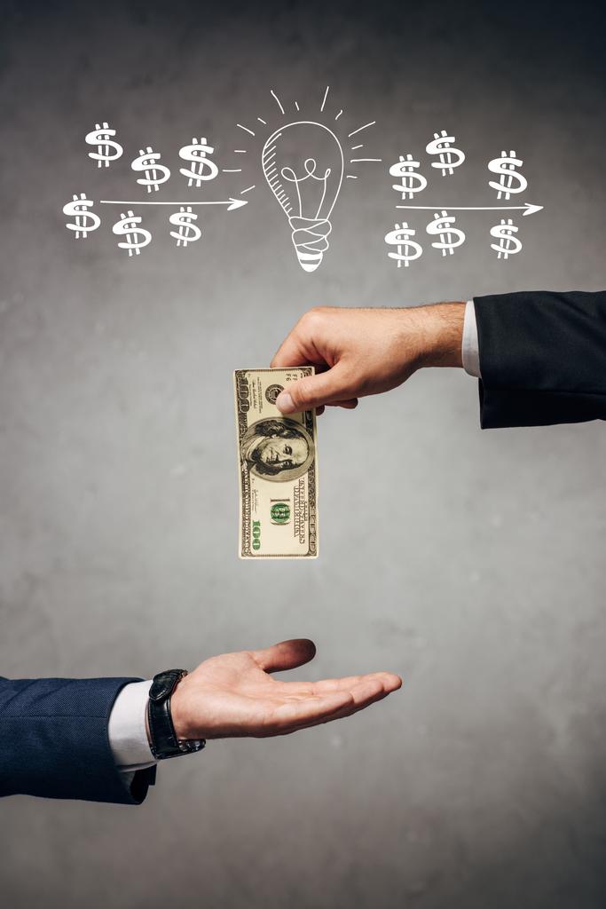 Mann gibt Geschäftsmann Geld auf grauem Hintergrund mit Glühbirne und Dollarzeichen - Foto, Bild