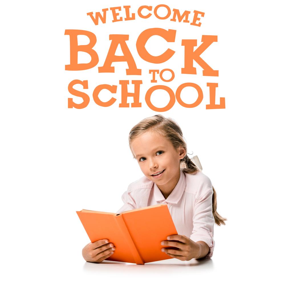 szczęśliwy uczeń trzyma pomarańczową książkę i uśmiecha się prawie witam z powrotem do szkolnych listów na białym  - Zdjęcie, obraz