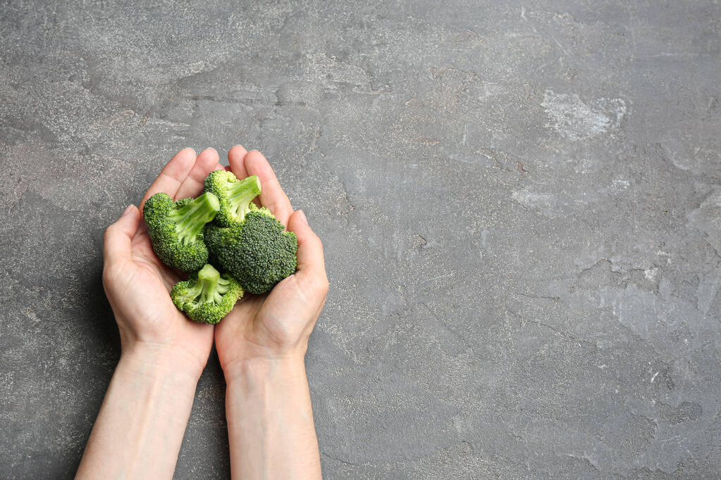 Broccoli verdi freschi da donna su tavolo in pietra grigia, vista dall'alto. Spazio per testo
 - Foto, immagini