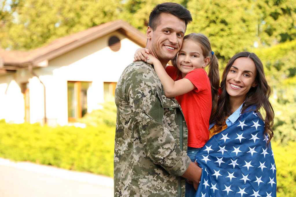 Katonai egyenruhás férfi és családja amerikai zászlóval a szabadban - Fotó, kép