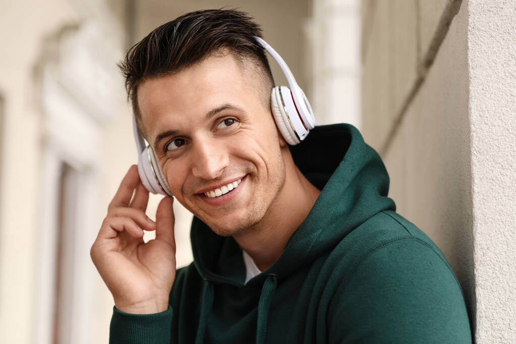 Portrait de beau jeune homme avec écouteurs écoutant de la musique à l'extérieur
 - Photo, image