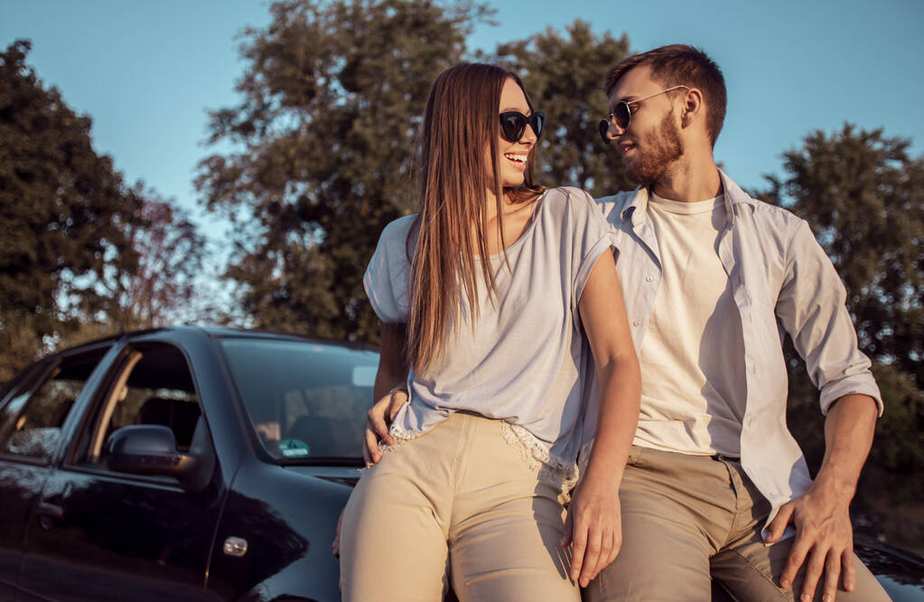 Fiatal férfi és nő beszél egy autó csuklya - Fotó, kép