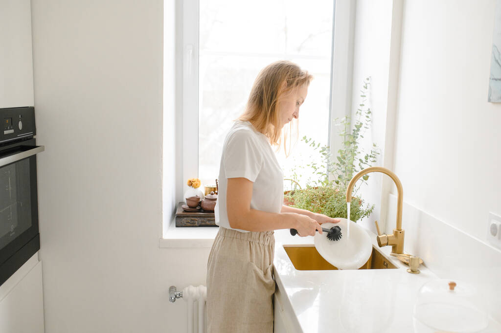 Een vrouw die afwas in de keuken. Sluit de hand van de vrouw. Huisvrouw schone vaat - Foto, afbeelding