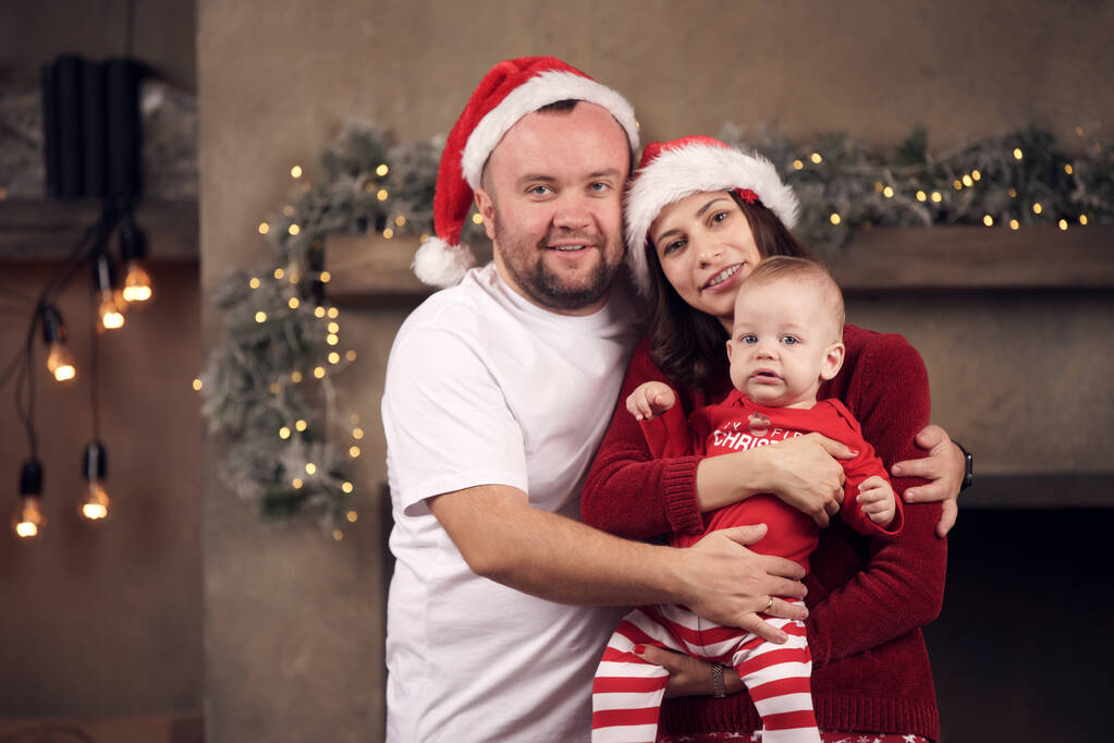Photo of parents in Santas caps with little son in apartment - Photo, Image