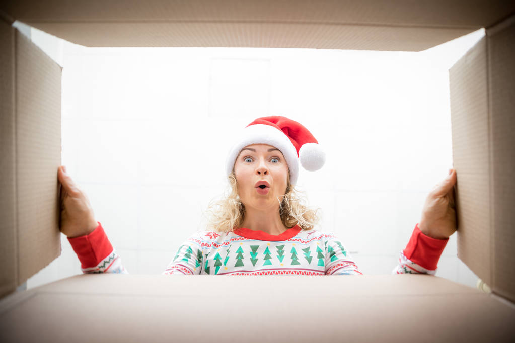 Yllättynyt nainen purkaa joululahja laatikko
 - Valokuva, kuva