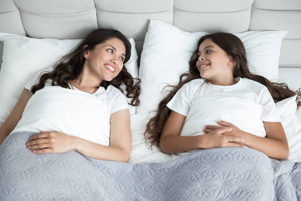 jovem bela mãe e seu bonito adolescente filha acabou de acordar juntos na cama
 - Foto, Imagem