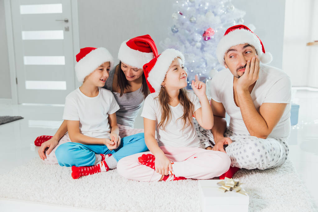 Padres e hijos felices intercambiando regalos cerca del árbol de Navidad en casa
 - Foto, Imagen