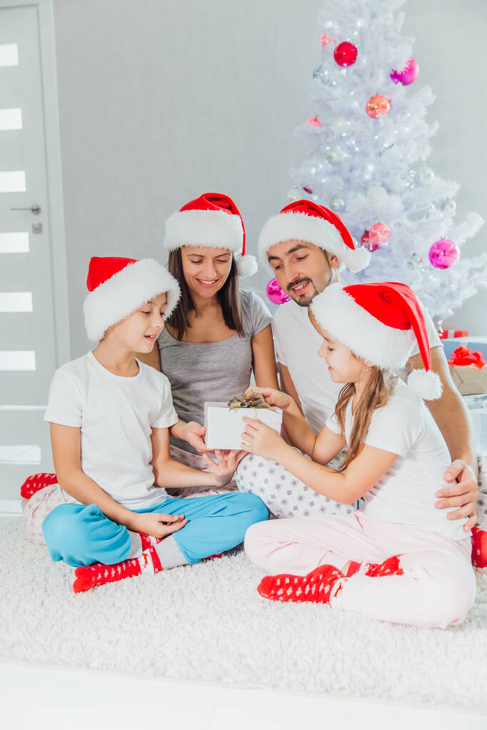 Молода сім'я святкує Різдво вдома. Щаслива молода сім'я насолоджується відпочинком разом
 - Фото, зображення