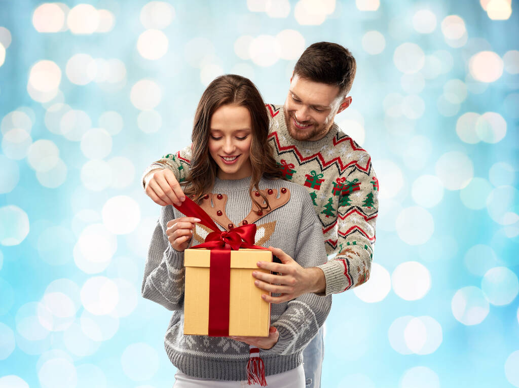 heureux couple en chandails de Noël avec boîte cadeau - Photo, image