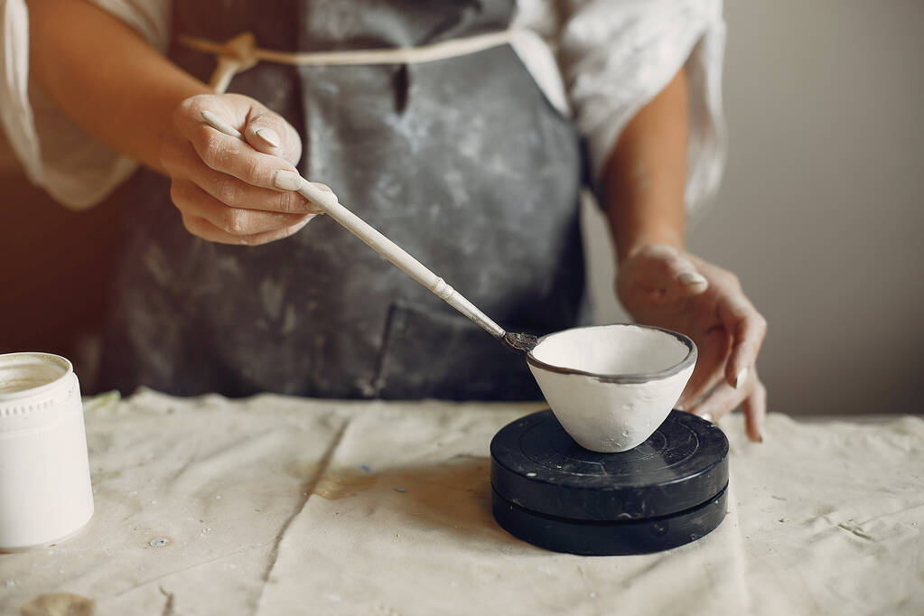 Een jonge vrouw maakt gerechten in een aardewerk - Foto, afbeelding