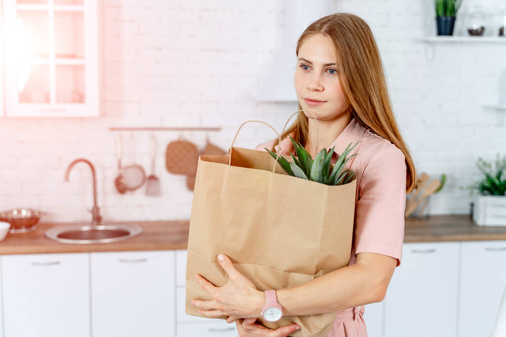 Frau mit dem Einkaufspaket in der Hand. Hintergrund Küche. Junge Frau mit gesunder Ernährung. - Foto, Bild