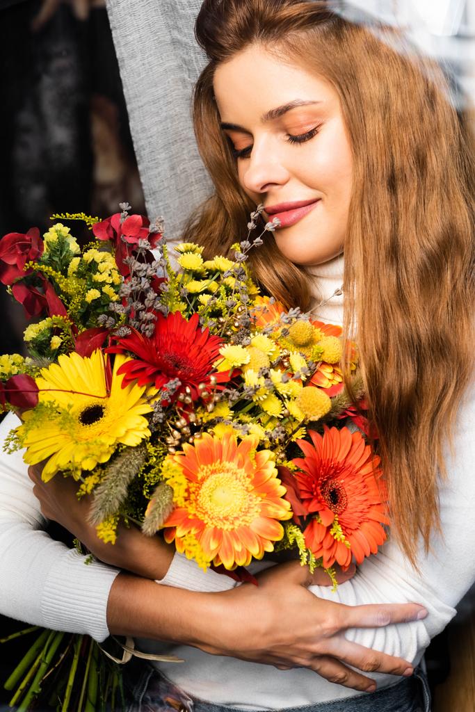 jolie femme rousse souriante avec bouquet de fleurs d'automne près de la fenêtre
  - Photo, image