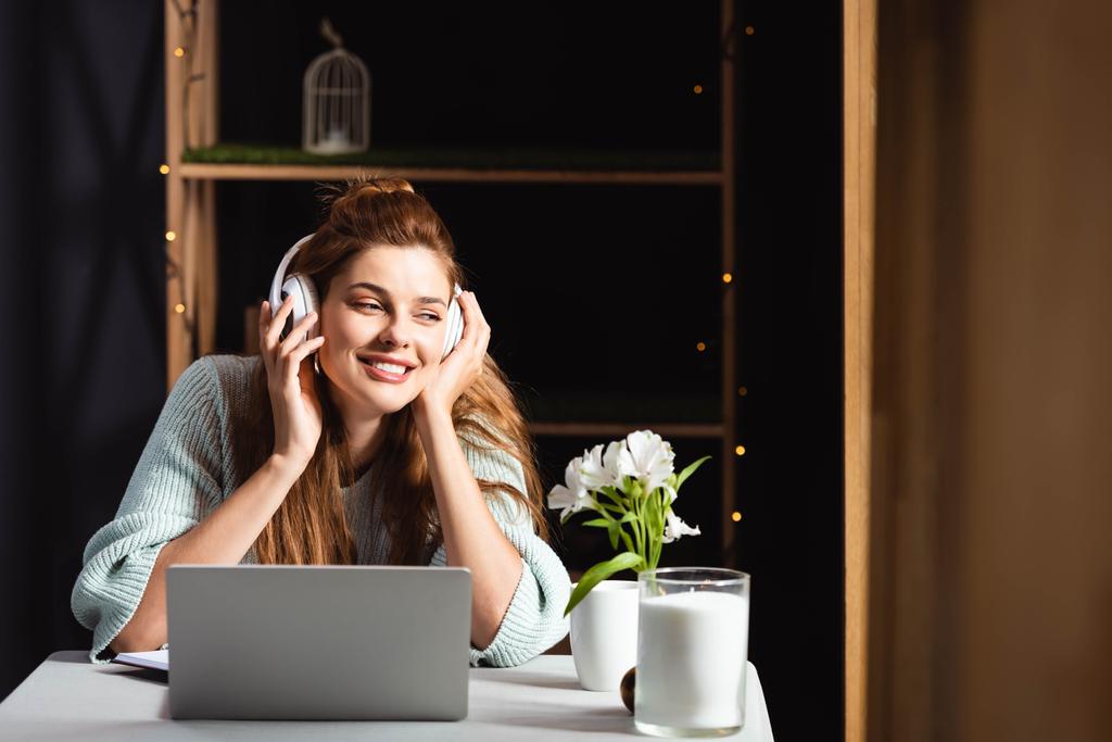 verträumte Frau mit Kopfhörern schaut Webinar auf Laptop im Café - Foto, Bild