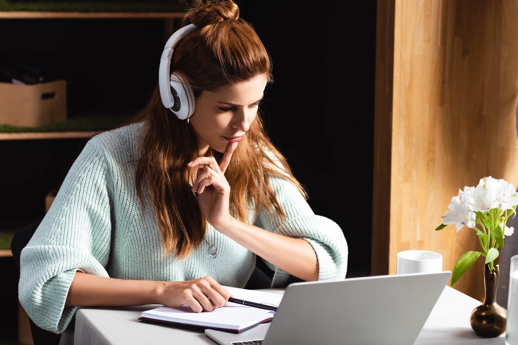 задумчивая женщина в наушниках учится онлайн с ноутбуком в кафе
 - Фото, изображение