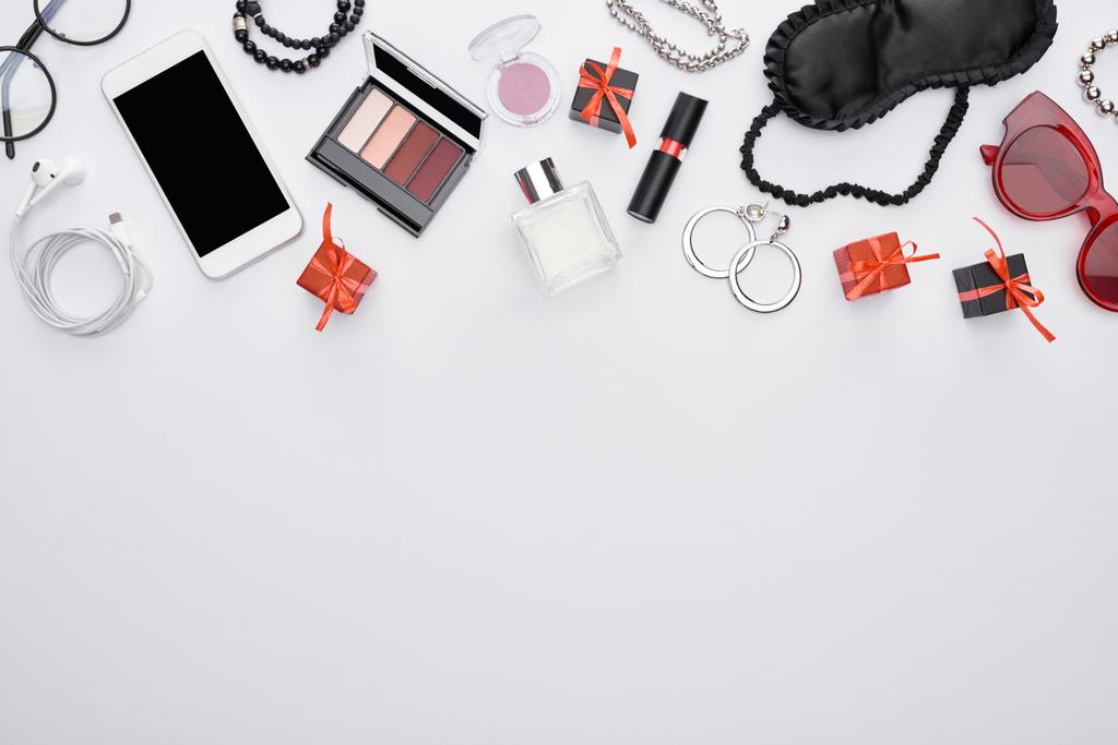 bovenaanzicht van gadget, geschenkdozen, slaapmasker, zonnebril, parfum, oorbellen, oortjes, armbanden, decoratieve cosmetica - Foto, afbeelding