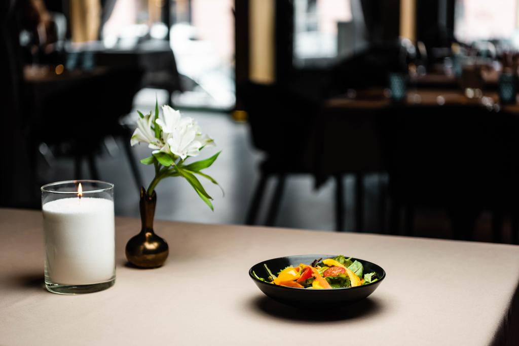 tányér salátával az asztalon gyertyával és virágokkal a kávézóban - Fotó, kép