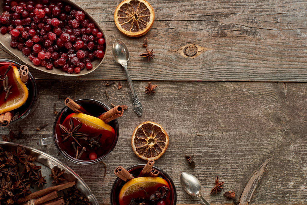 tetejére néző vörös fűszeres forralt bor bogyókkal, ánizs, narancs szeletek és fahéj fa rusztikus asztalon - Fotó, kép