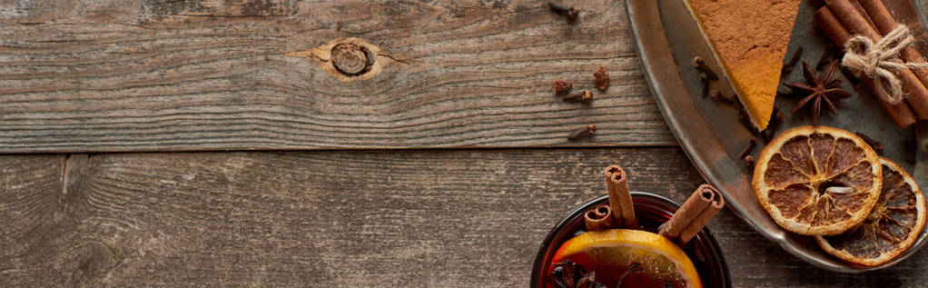 vista superior de vino tinto especiado con anís, rodajas de naranja y canela sobre mesa rústica de madera, plano panorámico
 - Foto, Imagen