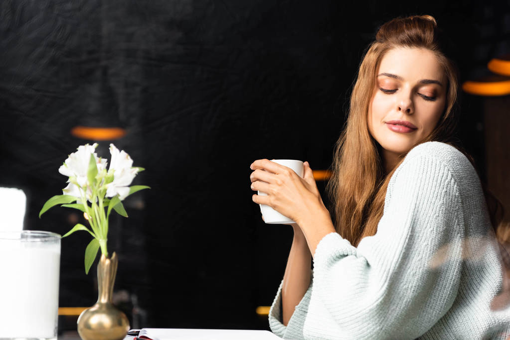 mulher macia segurando xícara de café no café com flores
 - Foto, Imagem