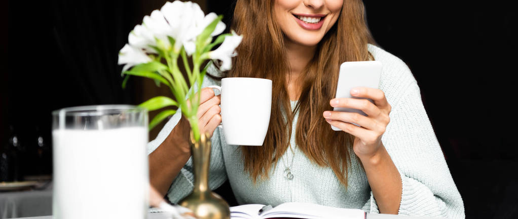 vista recortada de la mujer sonriente con taza de café usando teléfono inteligente en la cafetería
  - Foto, imagen