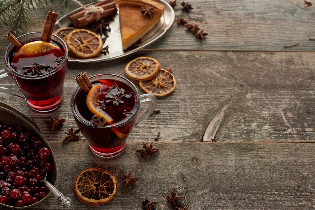 red spiced mulled wine near berries, anise, orange slices and cinnamon on wooden rustic table with copy space - Photo, Image