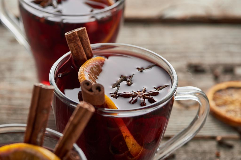 close up view of red spiced mulled wine with berries, anise, orange slice and cinnamon on wooden rustic table - Photo, Image