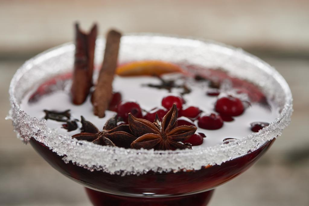 Nahaufnahme von rotem Glühwein mit Beeren, Anis, Orangenscheibe und Zimt im Glas mit Zucker - Foto, Bild
